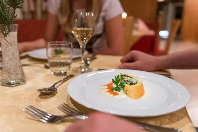 a plate of food on a table with a glass of wine at Hotel Kaserhof in Valles