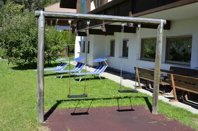 a group of chairs and swings in a yard at Pension Pichler in Chienes