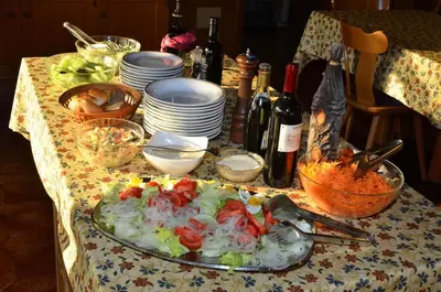 a table with a salad and plates and bottles of wine at Pension Pichler in Chienes