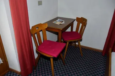 a small table and two chairs with red cushions at Pension Pichler in Chienes