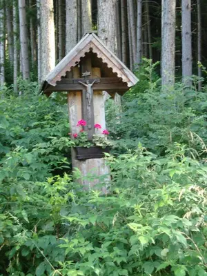 a cross with flowers on it in a forest at Winnewieser in Vandoies
