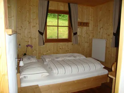 a bed in a wooden room with a window at Winnewieser in Vandoies