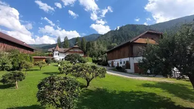 a green yard with buildings and trees and mountains at Mair am Hof - Farm - Maso - Bauernhof in San Lorenzo di Sebato