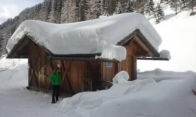 a man standing in front of a snow covered cabin at Mair am Hof - Farm - Maso - Bauernhof in San Lorenzo di Sebato