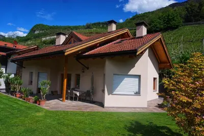 a white house with a roof with a lawn at Agritur Zuveith in Salorno sulla Strada del Vino