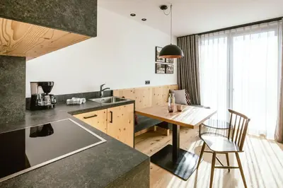 a kitchen with a wooden table and a dining room at Schloss Auer in Tirolo