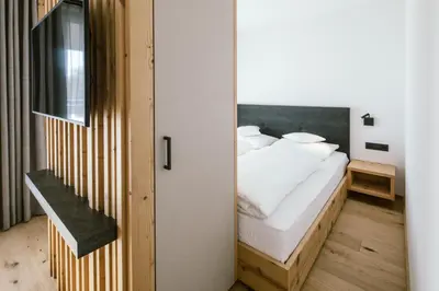 a bedroom with a bed with white sheets at Schloss Auer in Tirolo