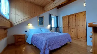 a bedroom with a bed with a blue comforter at Appartamento Fiocco Di Neve in Campitello di Fassa