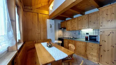 a kitchen with wooden cabinets and a wooden table at Appartamento Fiocco Di Neve in Campitello di Fassa