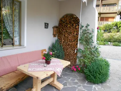 a patio with a wooden table and a bench at Garnì Conturina in Santa Cristina in Val Gardena