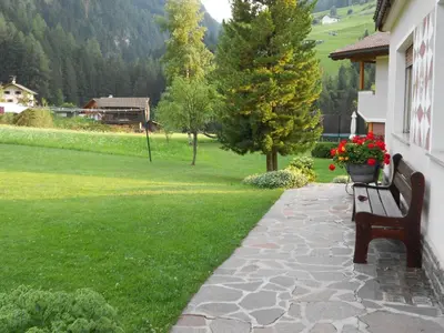 a bench sitting next to a yard with a field of flowers at Garnì Conturina in Santa Cristina in Val Gardena