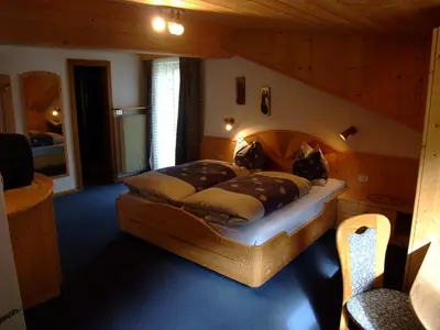 a bedroom with a large wooden bed in a room at Garnì Conturina in Santa Cristina in Val Gardena