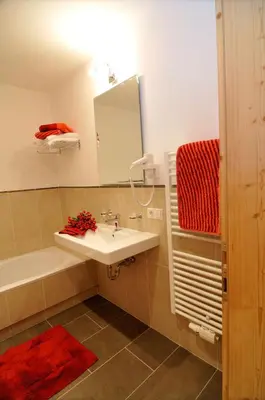 a bathroom with a sink and a tub and a mirror at Chalet Regina in Selva di Val Gardena