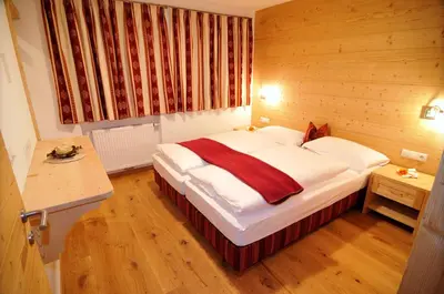 a bedroom with a large bed with a wooden wall at Chalet Regina in Selva di Val Gardena