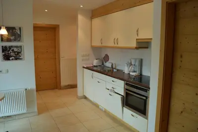 a kitchen with white cabinets and a sink and a stove at Chalet Regina in Selva di Val Gardena