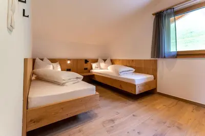 two beds in a room with a window at Gasthof Videgg in Schenna