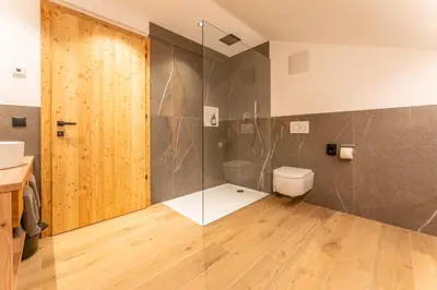 a bathroom with a toilet and a glass shower at Gasthof Videgg in Schenna