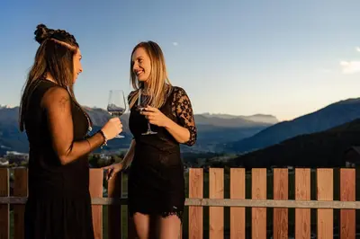two women standing next to a fence drinking wine at Sweet Dolomiti Sonneck in Maranza
