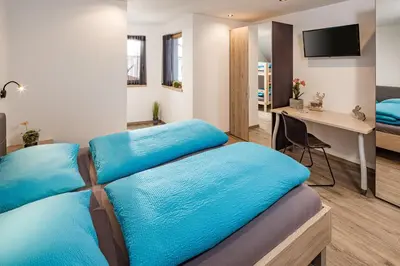 a bedroom with two blue beds and a desk at Sweet Dolomiti Sonneck in Maranza