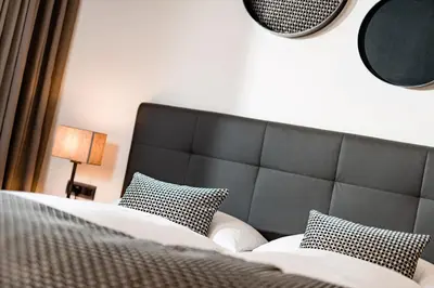a bedroom with a bed with a black headboard and pillows at Hotel Brunnhofer in Tirolo