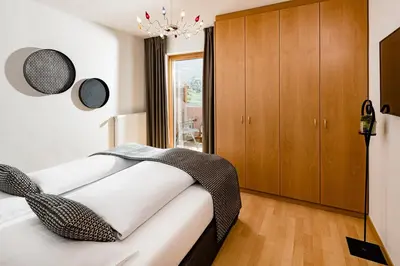 a bedroom with a bed and a wooden cabinet at Hotel Brunnhofer in Tirolo
