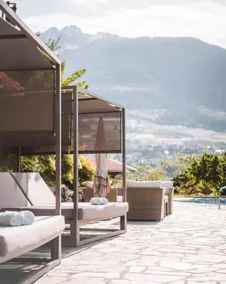 a patio with couches and a view of the mountains at Hotel Brunnhofer in Tirolo