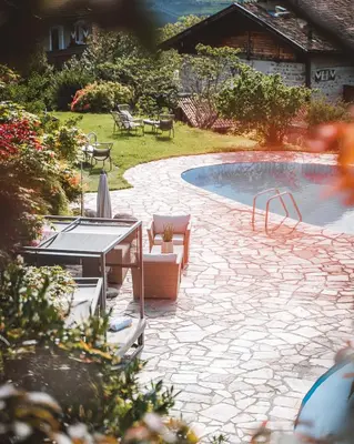 a backyard with a swimming pool with chairs and a table at Hotel Brunnhofer in Tirolo