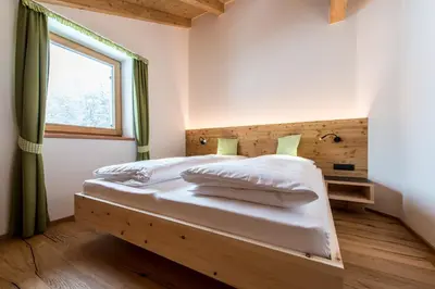 a bedroom with a bed with a wooden headboard and a window at Rauchenbichlerhof in Brunico