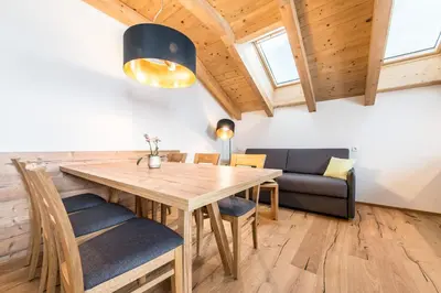 a dining room with a wooden table and chairs at Rauchenbichlerhof in Brunico