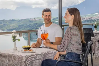 a man and woman sitting at a table with a drink at Viridis Hotel in Revò