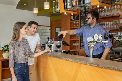 a group of people standing at a bar pouring wine at Viridis Hotel in Revò