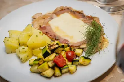 a plate of food with meat and potatoes on a table at Viridis Hotel in Revò