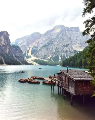 a house on a dock on a lake with boats at Lienharterhof in Monguelfo