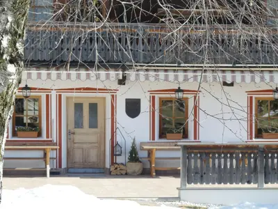 a house with two benches and a door at Lienharterhof in Monguelfo