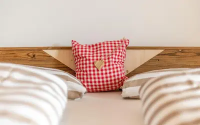 a red and white pillow on the headboard of a bed at Moarhof in Oberbozen in Soprabolzano