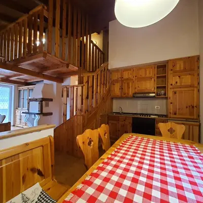 a kitchen with a table with a red and white checkered table cloth at Casa Maddalena in Canazei