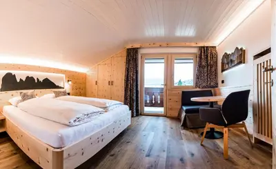 a bedroom with a bed and a desk and a table at Cesa Paula in Selva di Val Gardena