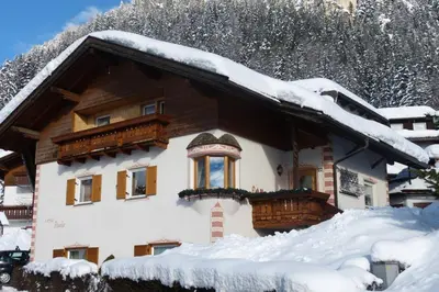 a house covered in snow with snow on the roof at Cesa Paula in Selva di Val Gardena