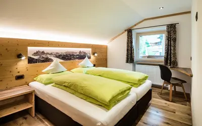 a bedroom with a large bed with green sheets at Cesa Paula in Selva di Val Gardena