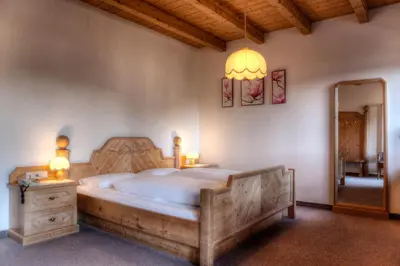 a bedroom with a wooden bed with two lamps and a mirror at Pension Panorama in Monguelfo