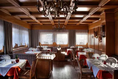 a restaurant with tables and chairs and a chandelier at Pension Panorama in Monguelfo