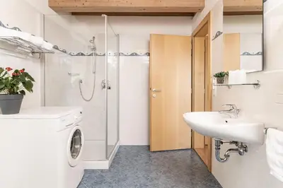a bathroom with a sink and a washing machine at Haus Sauvignon in Cortaccia