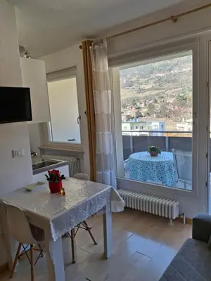 a living room with a table and a large window at Merano Panoramablick ruhig gelegen in Merano