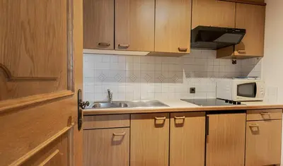 a kitchen with wooden cabinets and a sink and a microwave at Residence A Val in San Cassiano