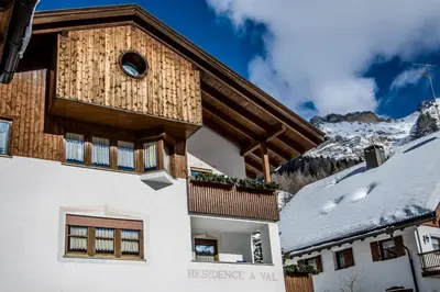 a house in the mountains with snow on the ground at Residence A Val in San Cassiano