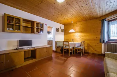 a room with a table with a television and a dining room at Residence A Val in San Cassiano