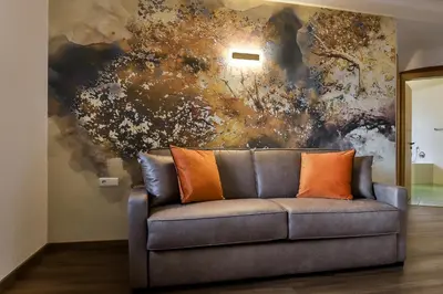 a couch with two orange pillows in front of a painting at Residence Kronenwirt in Parcines
