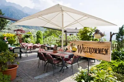 a bird sitting on a table under an umbrella at Residence Kronenwirt in Parcines