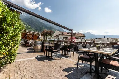 a patio with tables and chairs on a roof at Residence Kronenwirt in Parcines