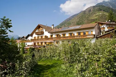a building on a hill with mountains in the background at Residence Kronenwirt in Parcines